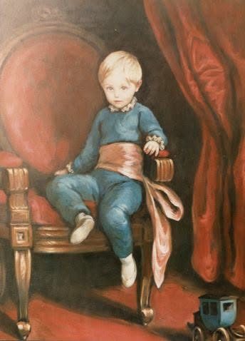 Niño con traje azul y faja de seda sentado en una silla de madera, con un carrito de juguete en el suelo